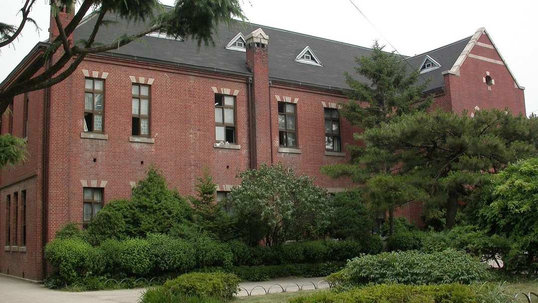 소나무와 정원수에 둘러싸인 붉은 벽돌 학교 건물